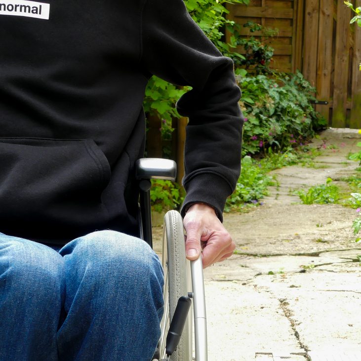 Eine behinderte Person in einem Rollstuhl auf einem Weg