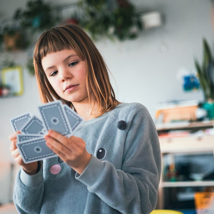 Junges Mädchen sieht sich unterschiedliche Spielkarten an