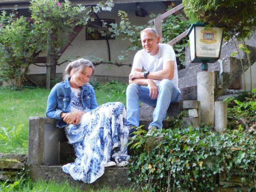 Kim Genetsch und Sönke Grajetzky sitzen lächelnd in ihrem Garten
